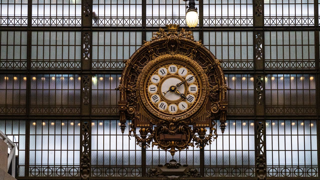 Vue plongeante sur la grande horloge du musée d'Orsay à Paris, lumière dorée et ambiance feutrée