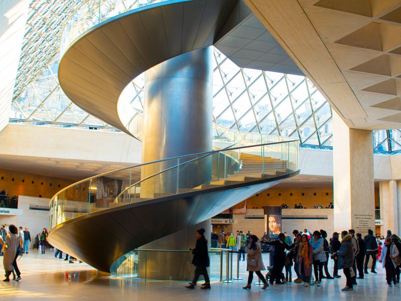 Salle d'exposition temporaire au Louvre avec des tableaux de Léonard de Vinci sous un éclairage tamisé, Paris